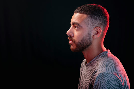 Man facing the left looking straight ahead in a gray t-shirt against a black background